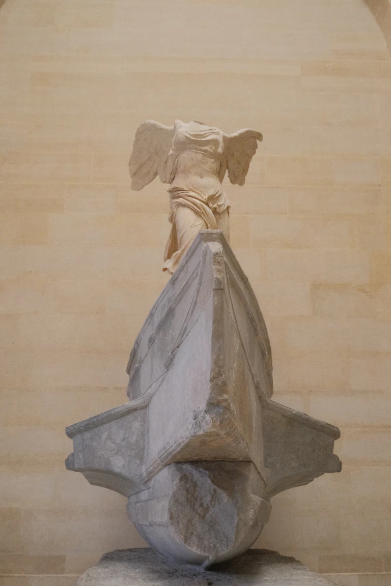 Escultura clásica de la Victoria alada sobre la proa de un barco