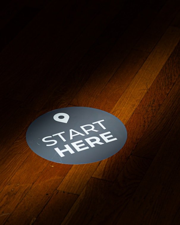 A round floor sticker with "start here" text.