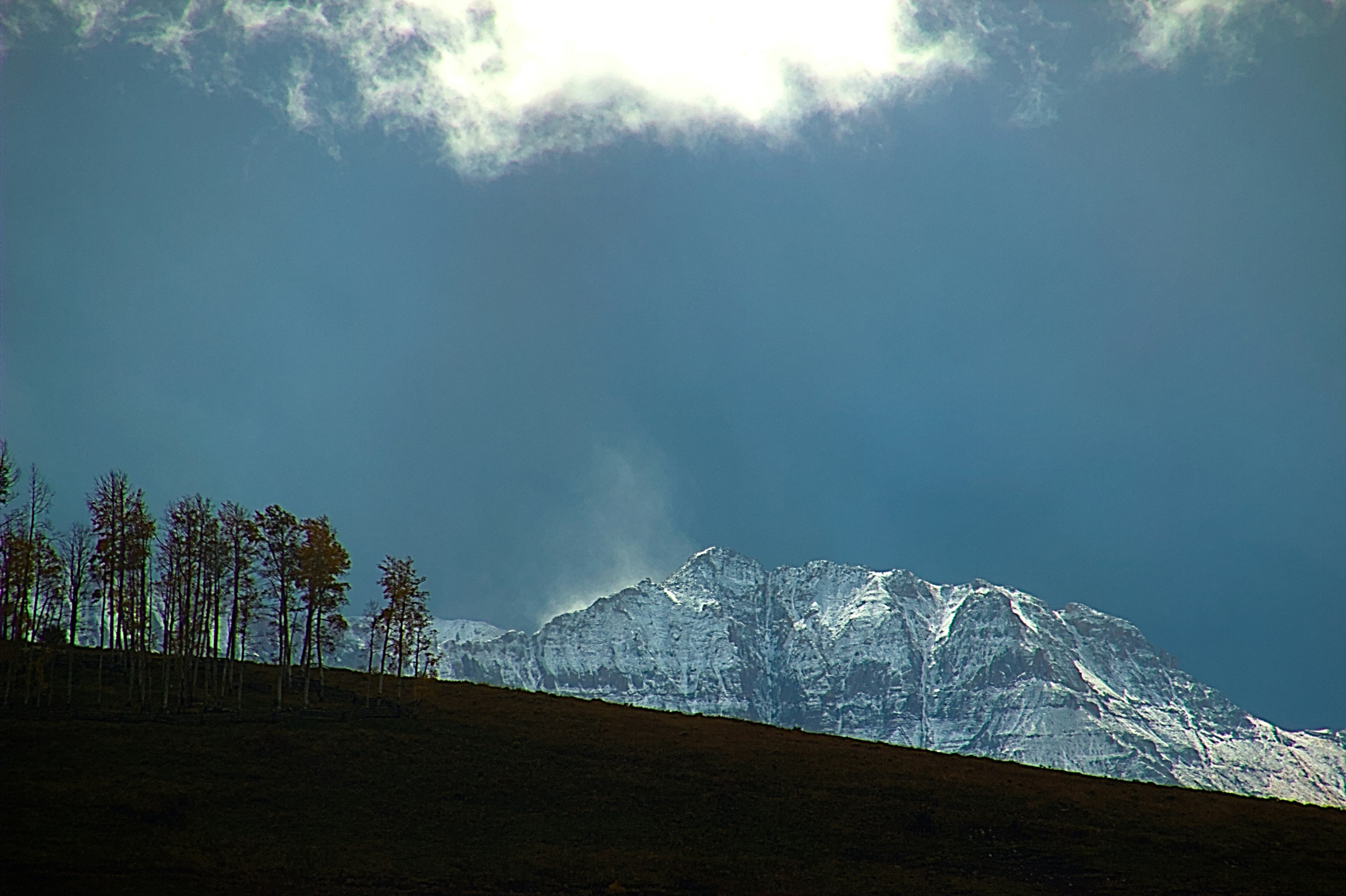 Snow-capped mountain peak under dramatic cloudy sky.