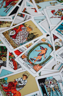 A pile of scattered tarot cards with colorful illustrations.