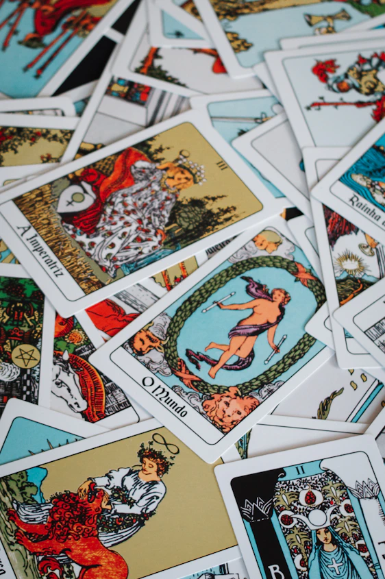 A pile of scattered tarot cards with colorful illustrations.