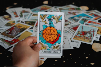 Hand holding a tarot card with wheel of fortune