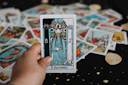 Hand holding a tarot card over a spread.