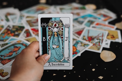 Hand holding a tarot card over a spread.