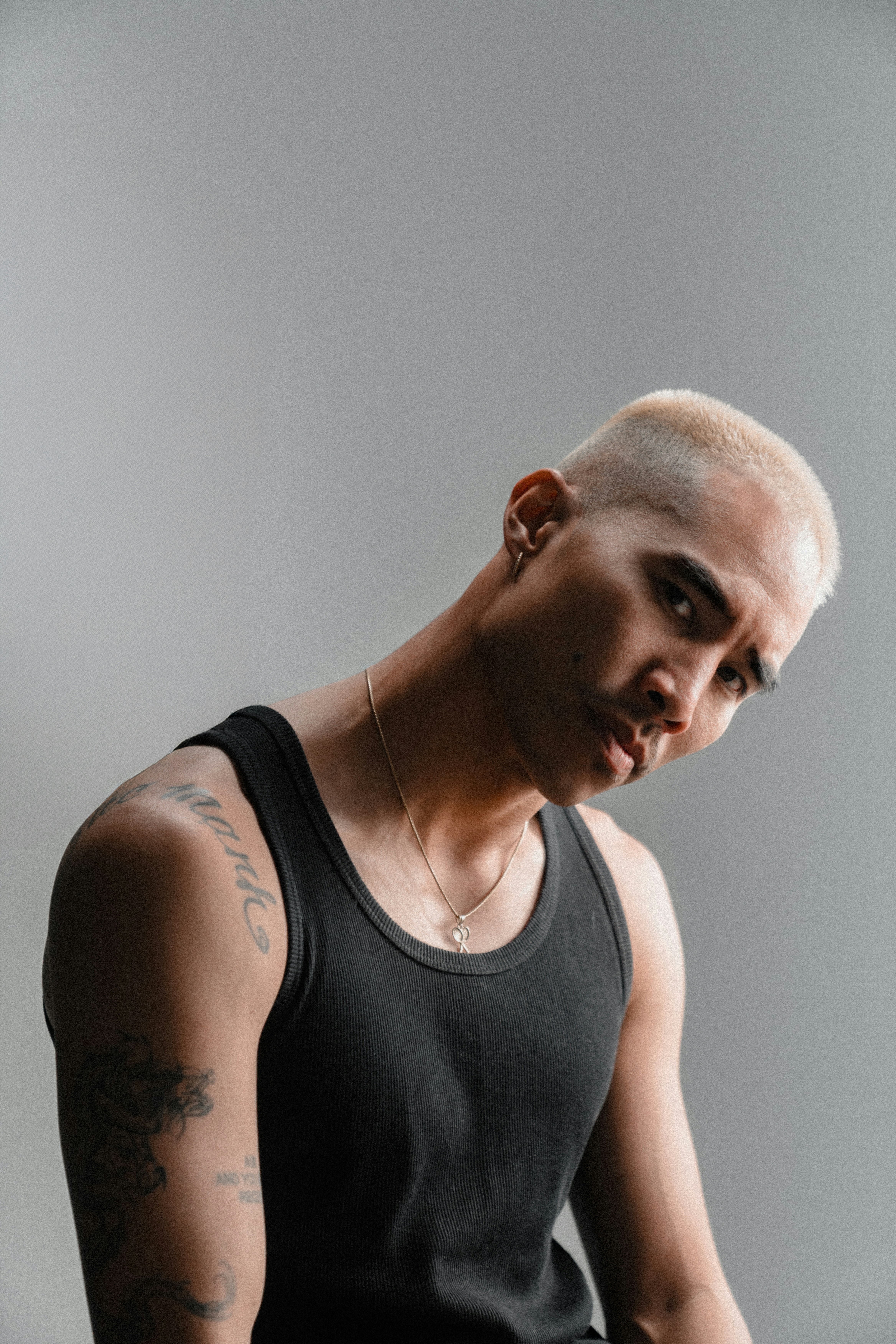 Man with short blonde hair wearing tank top