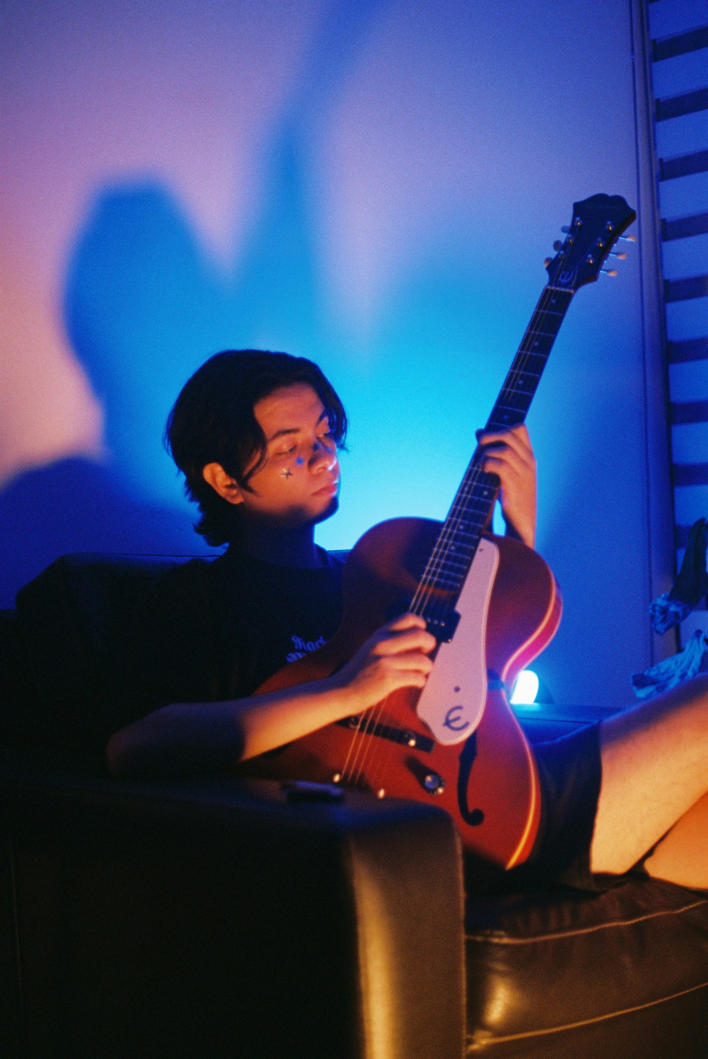 Man holding an acoustic guitar with blue lighting