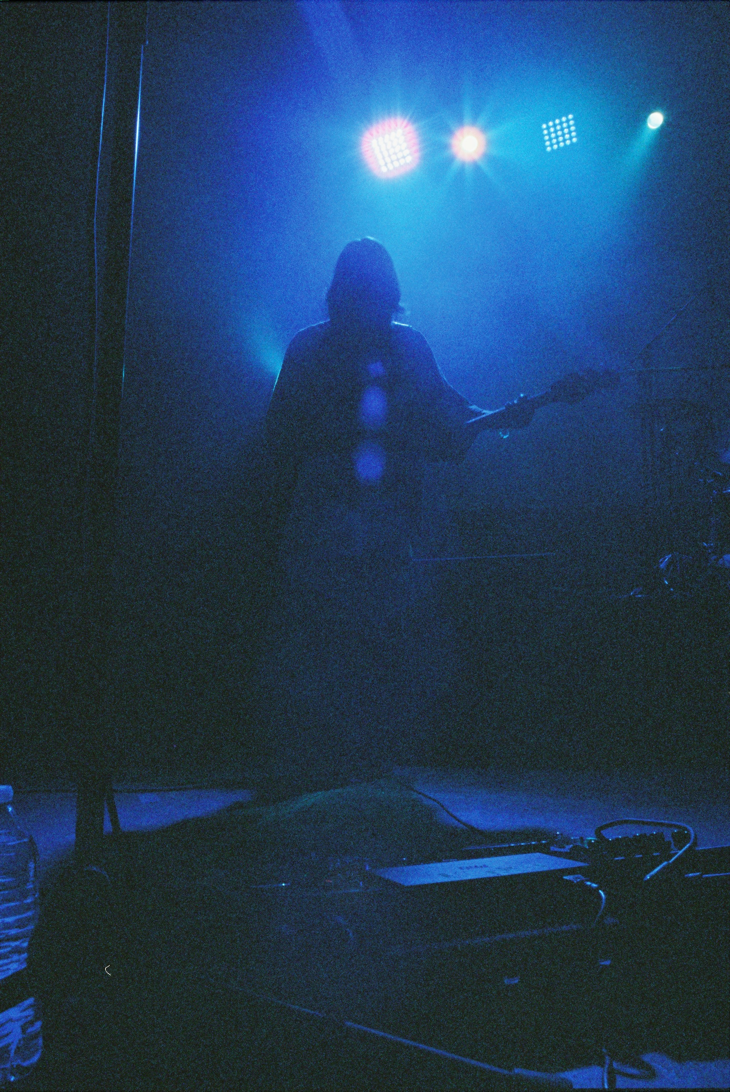 Musician playing guitar on a dimly lit stage.