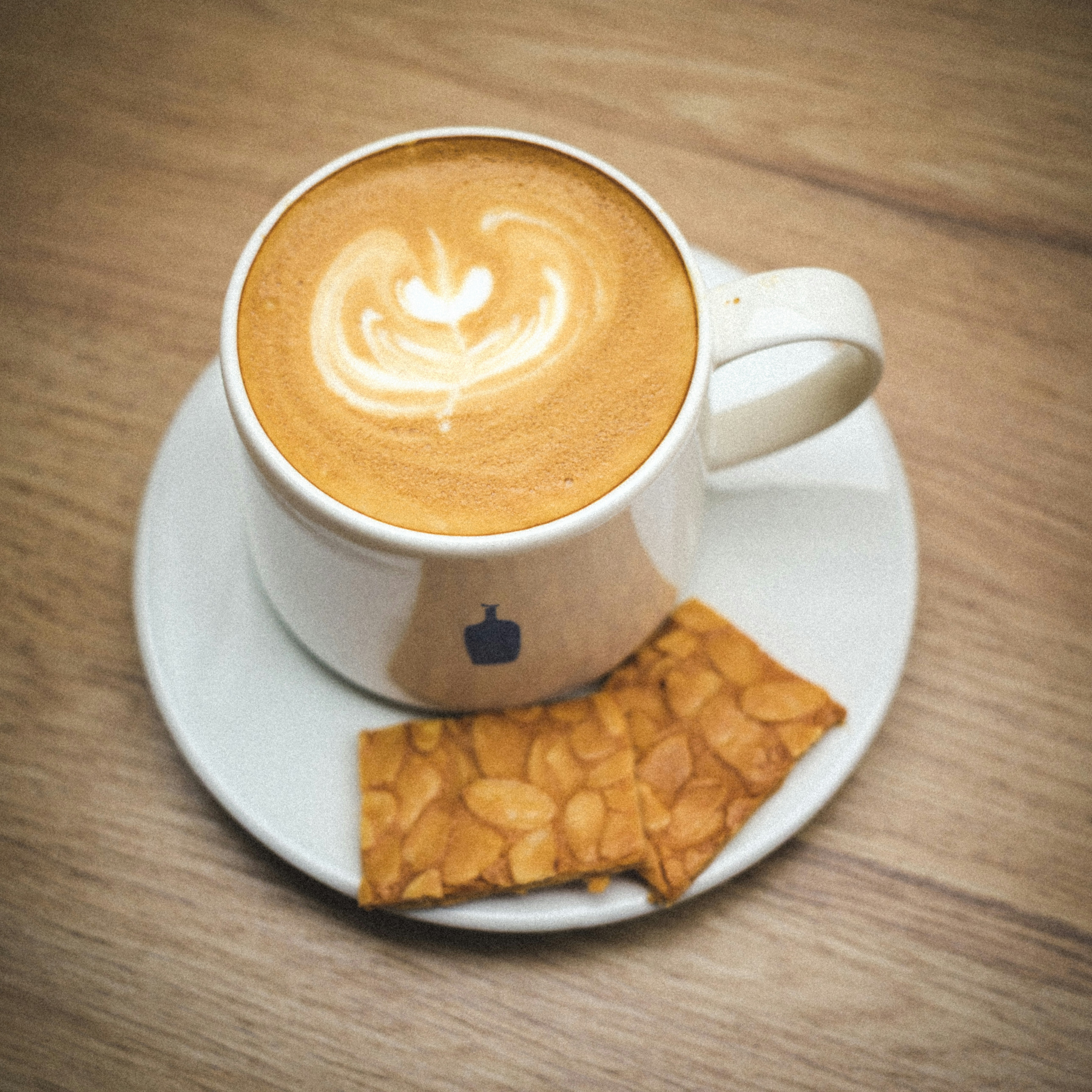 A cup of coffee with latte art and a cookie.