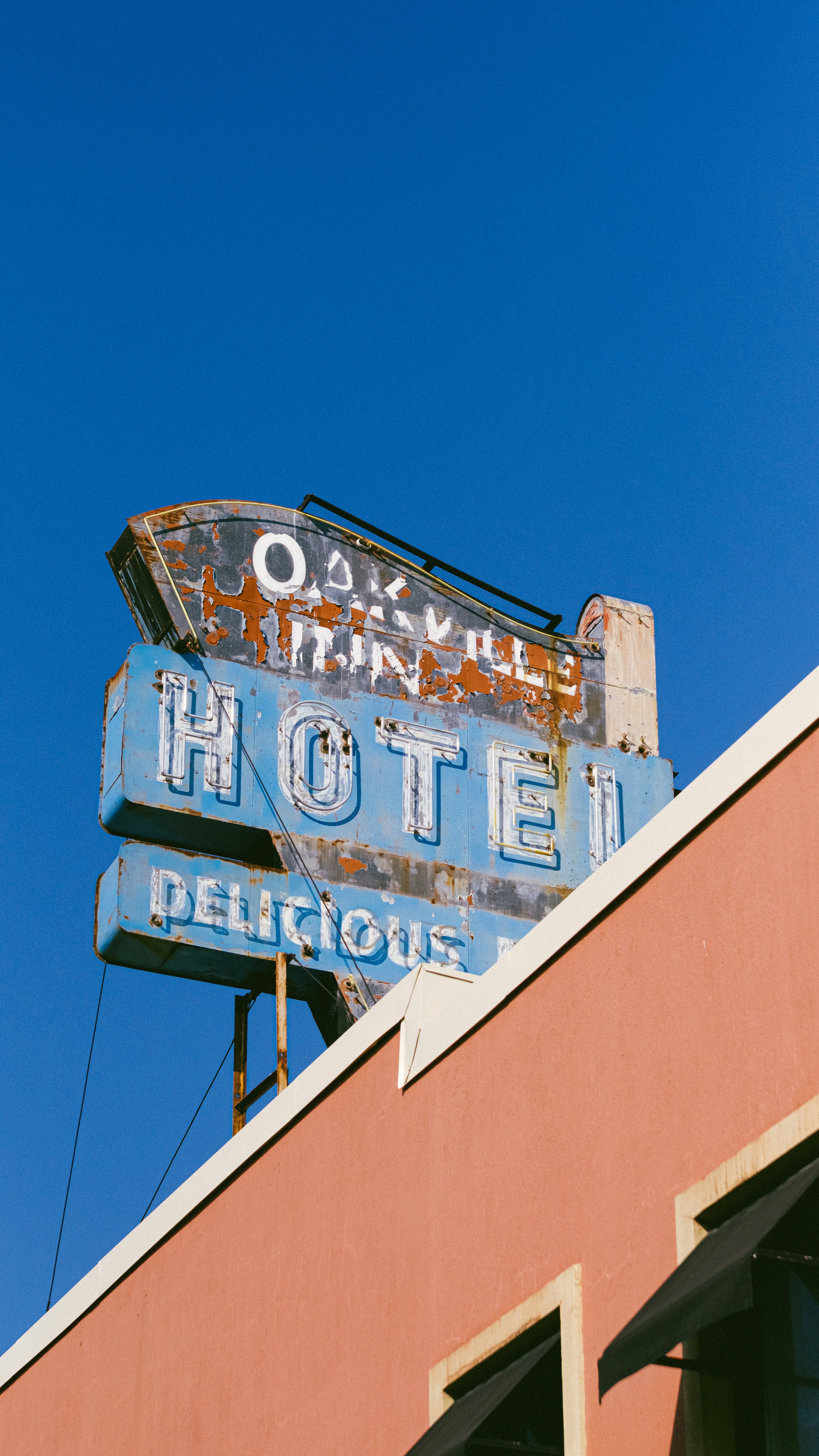 Old neon hotel sign against a clear blue sky.
