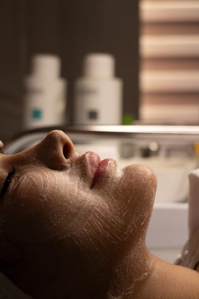 Woman's face with cleansing foam during facial treatment.