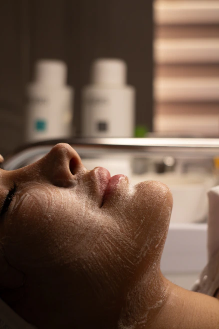 Woman's face with cleansing foam during facial treatment.