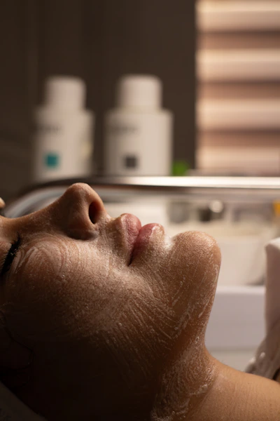 Woman's face with cleansing foam during facial treatment.