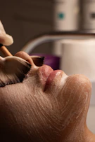 Facial treatment with brush applying white cream to face