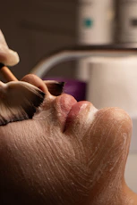 Facial treatment with brush applying white cream to face