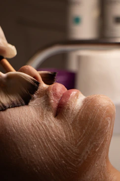 Facial treatment with brush applying white cream to face