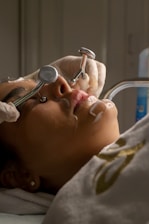 Woman receiving facial treatment with metal tools.