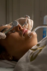 Woman receiving facial treatment with metal tools.