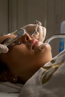 Woman receiving facial treatment with metal tools.