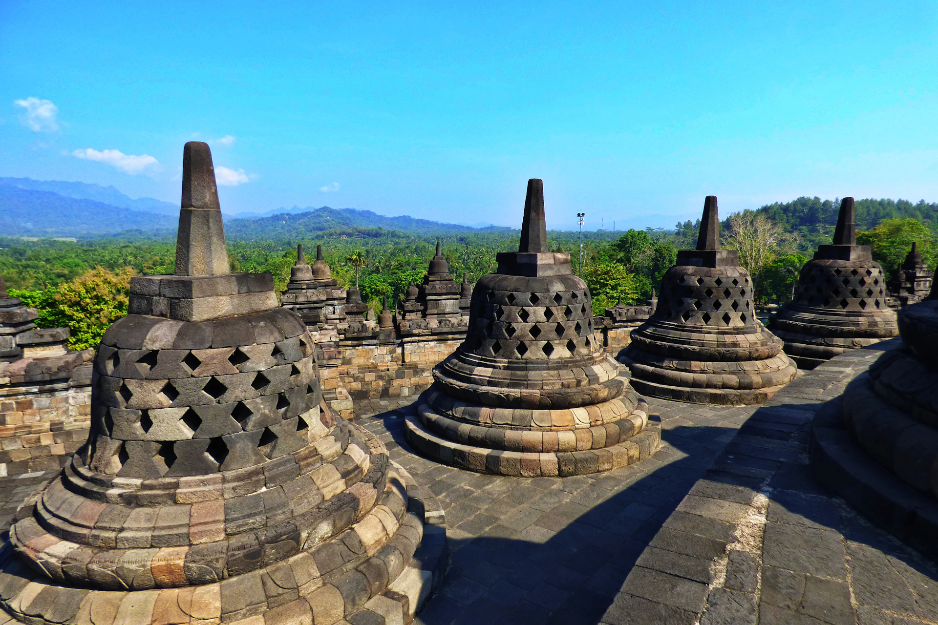 Ancient stupas at borobudur temple complex under blue sky