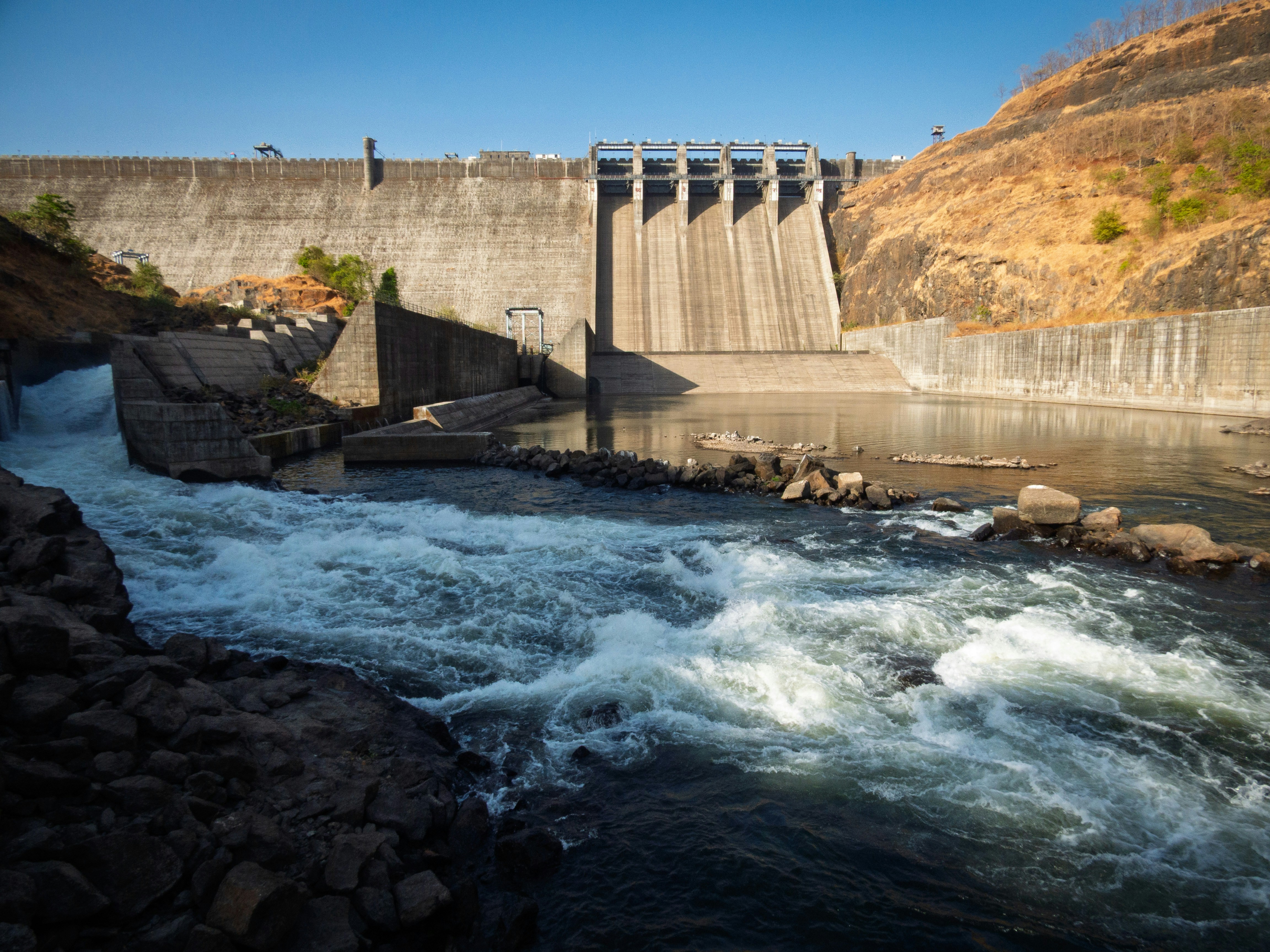 A large concrete dam with water flowing downstream.