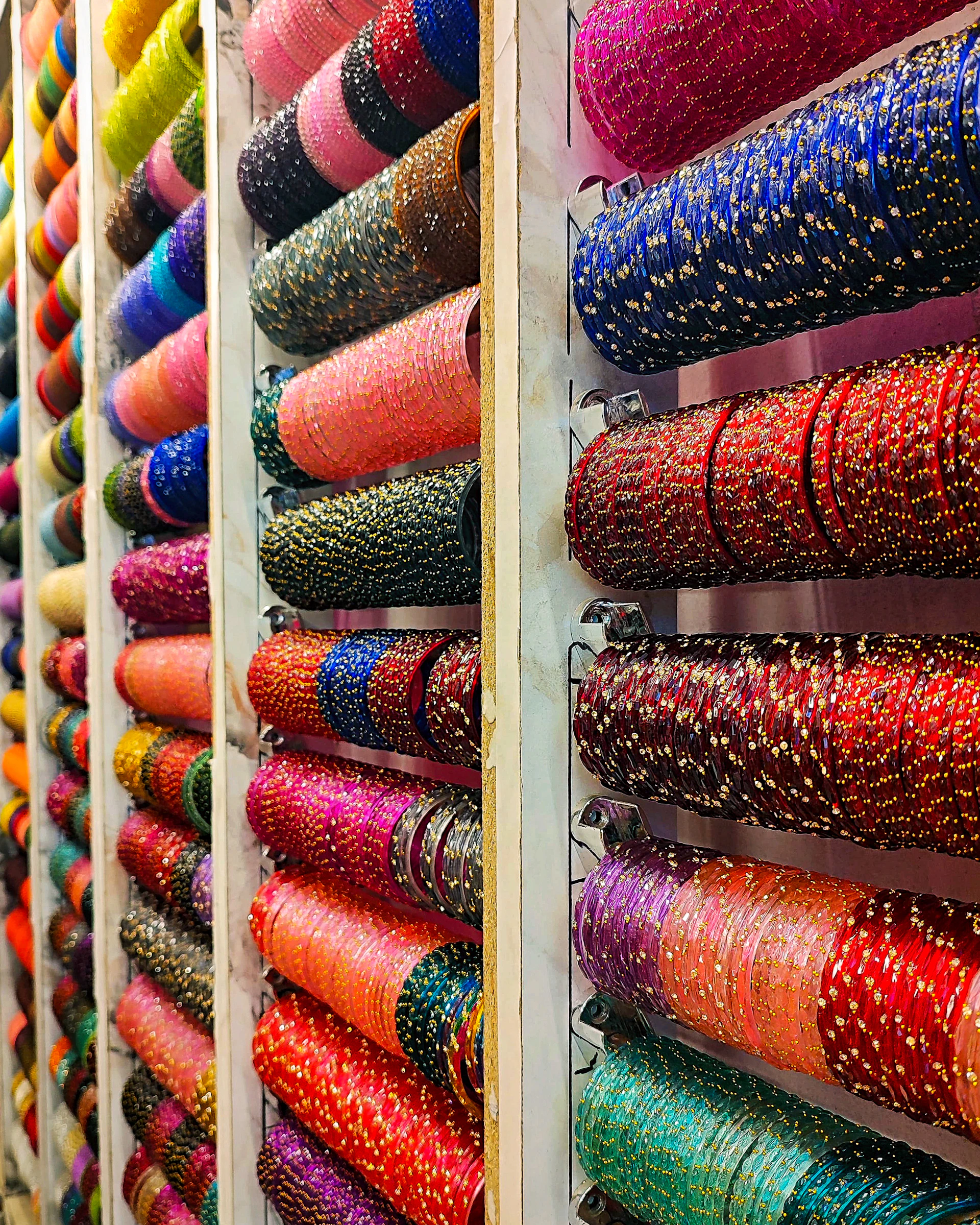 Colorful bangles displayed on shelves in a store.