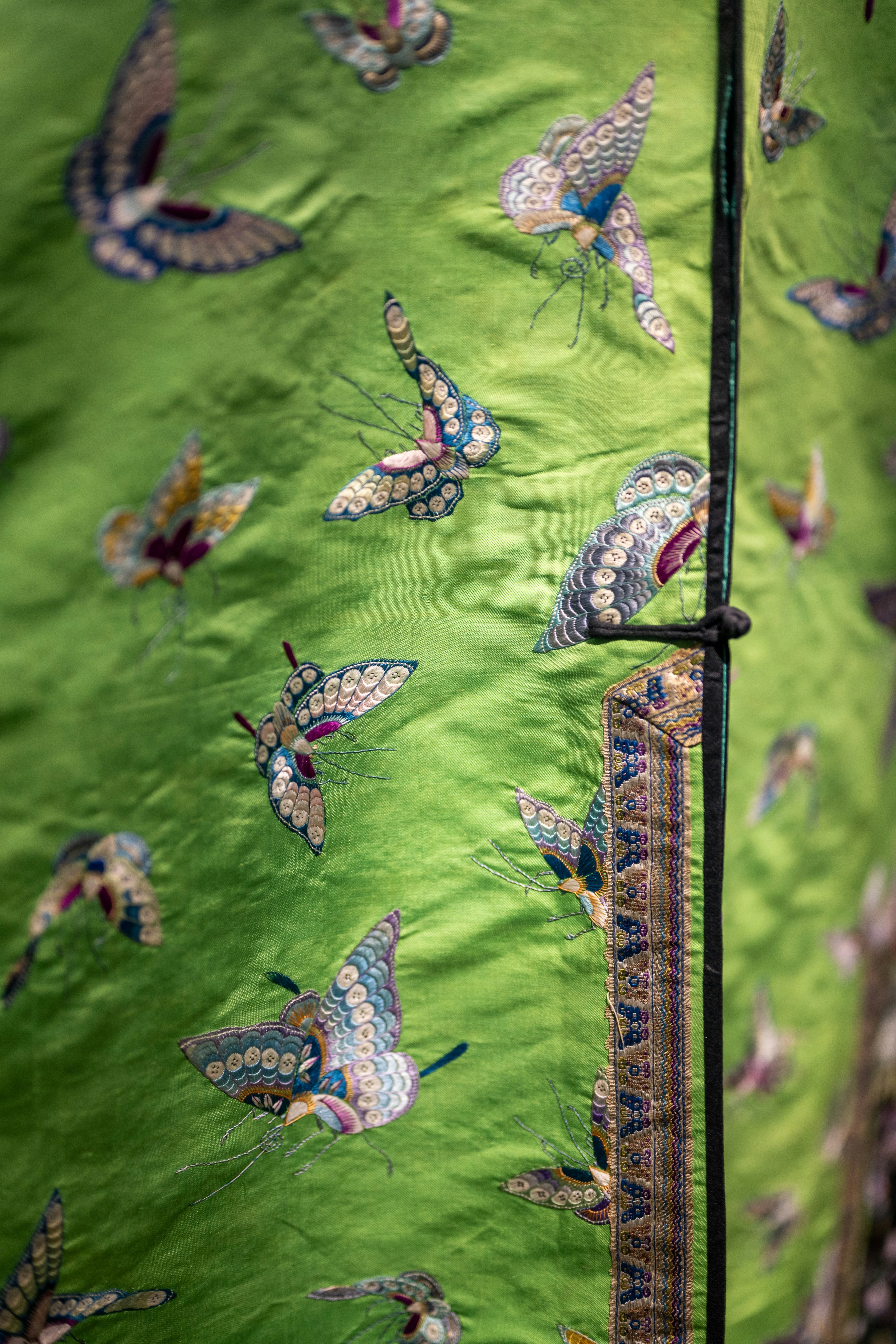 Embroidered butterflies on a green silk garment.