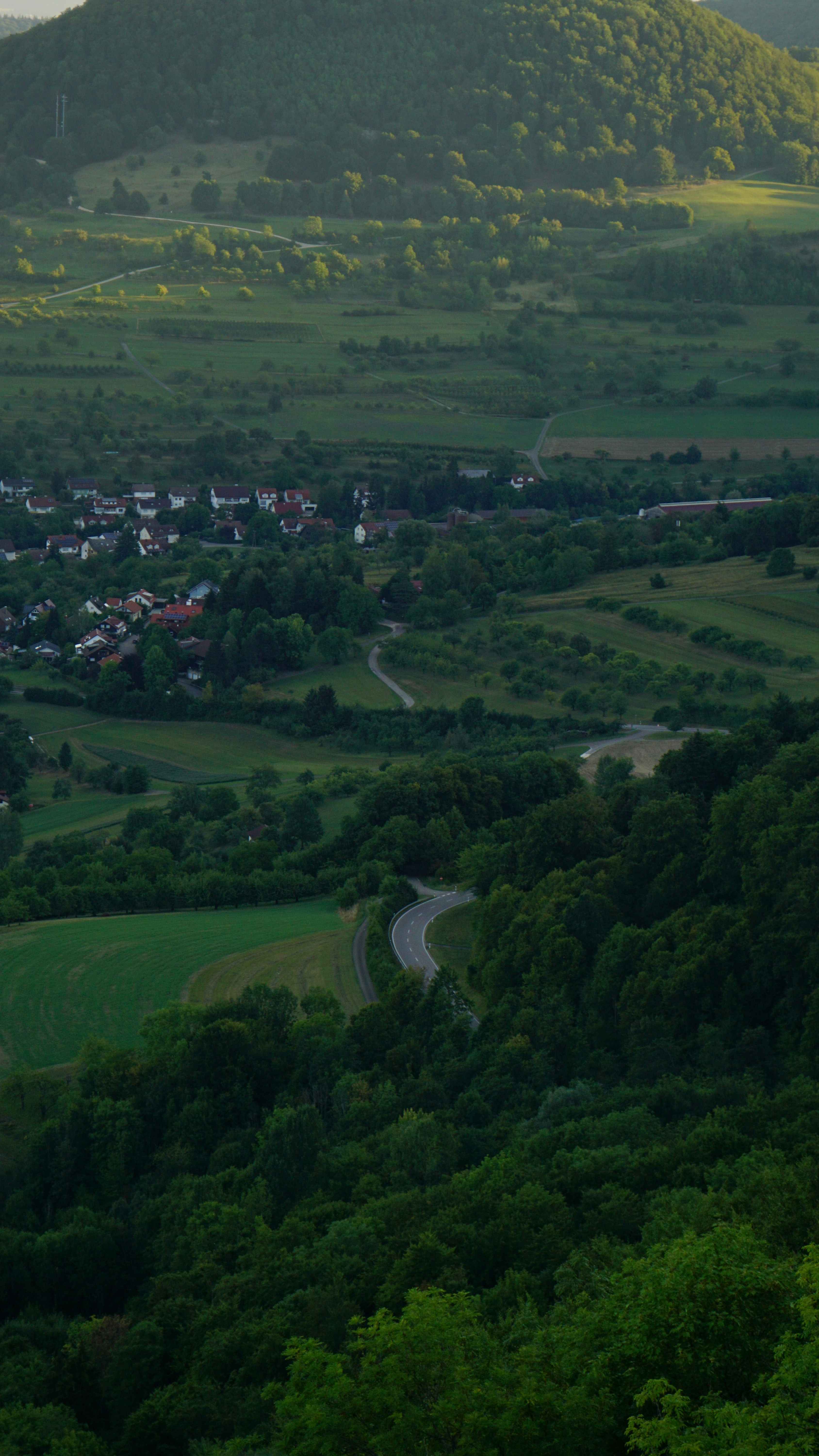 A winding road leads through a lush green valley.