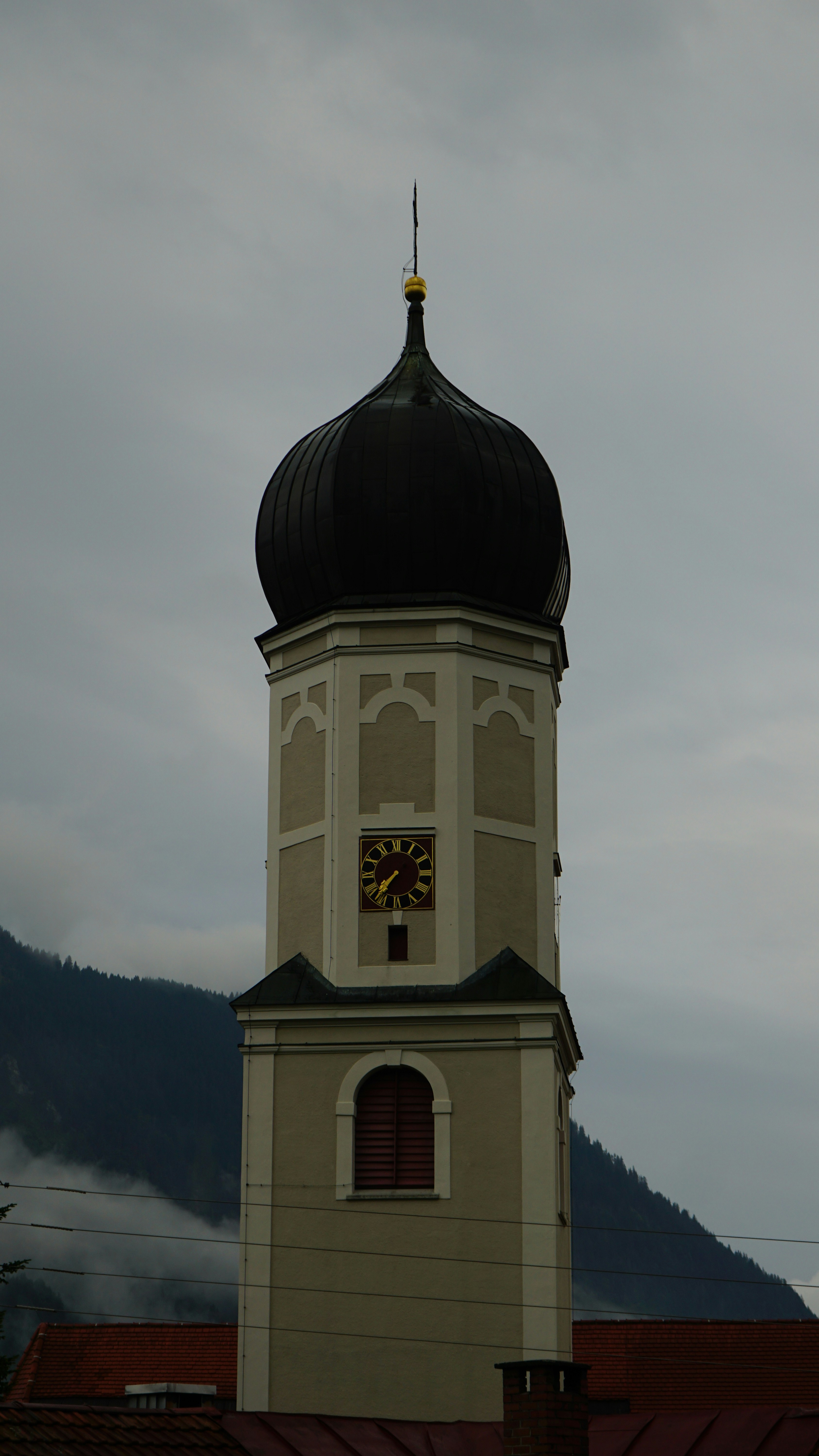 A church tower with a clock against a cloudy sky.