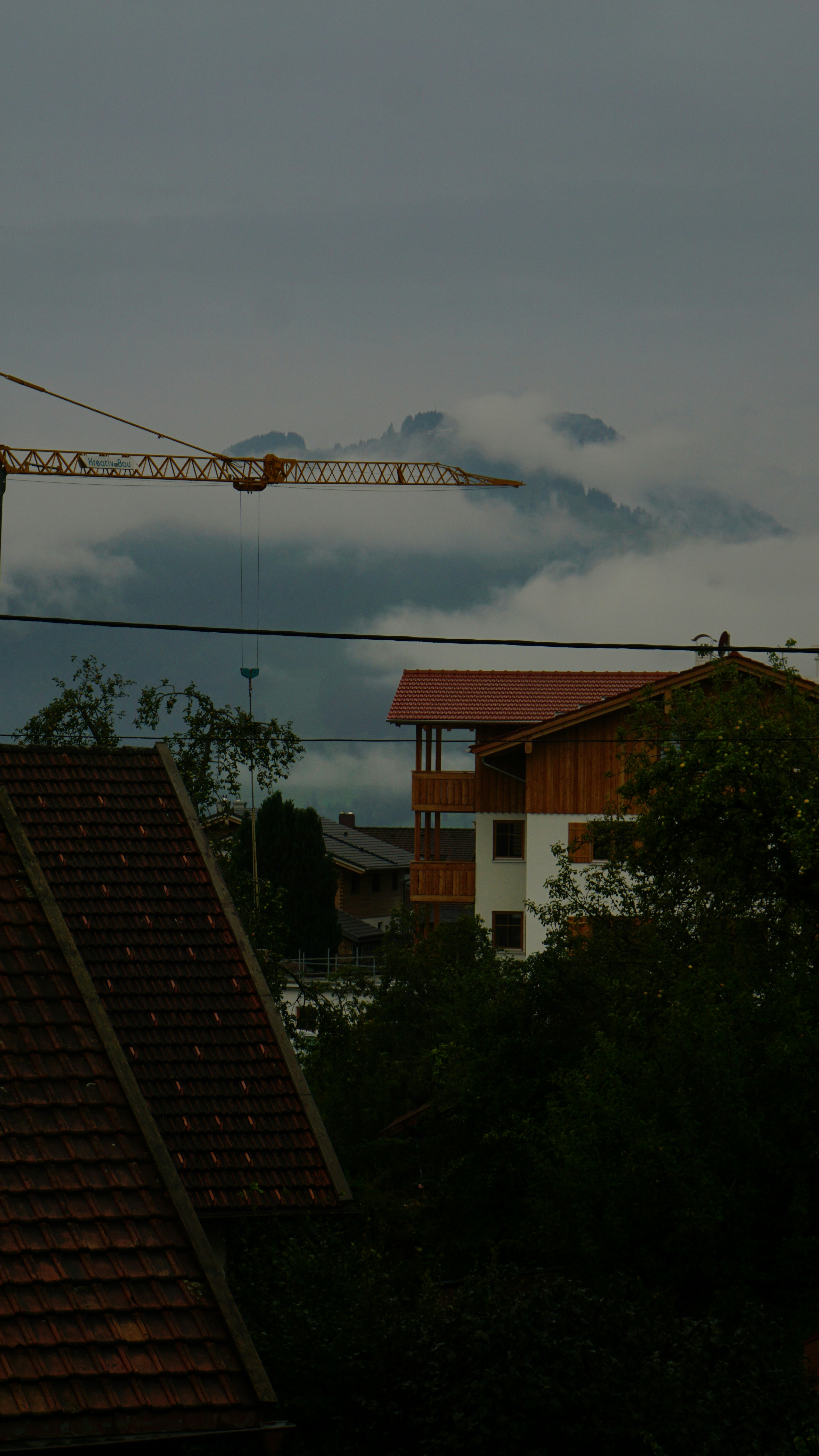Crane and buildings against misty mountains
