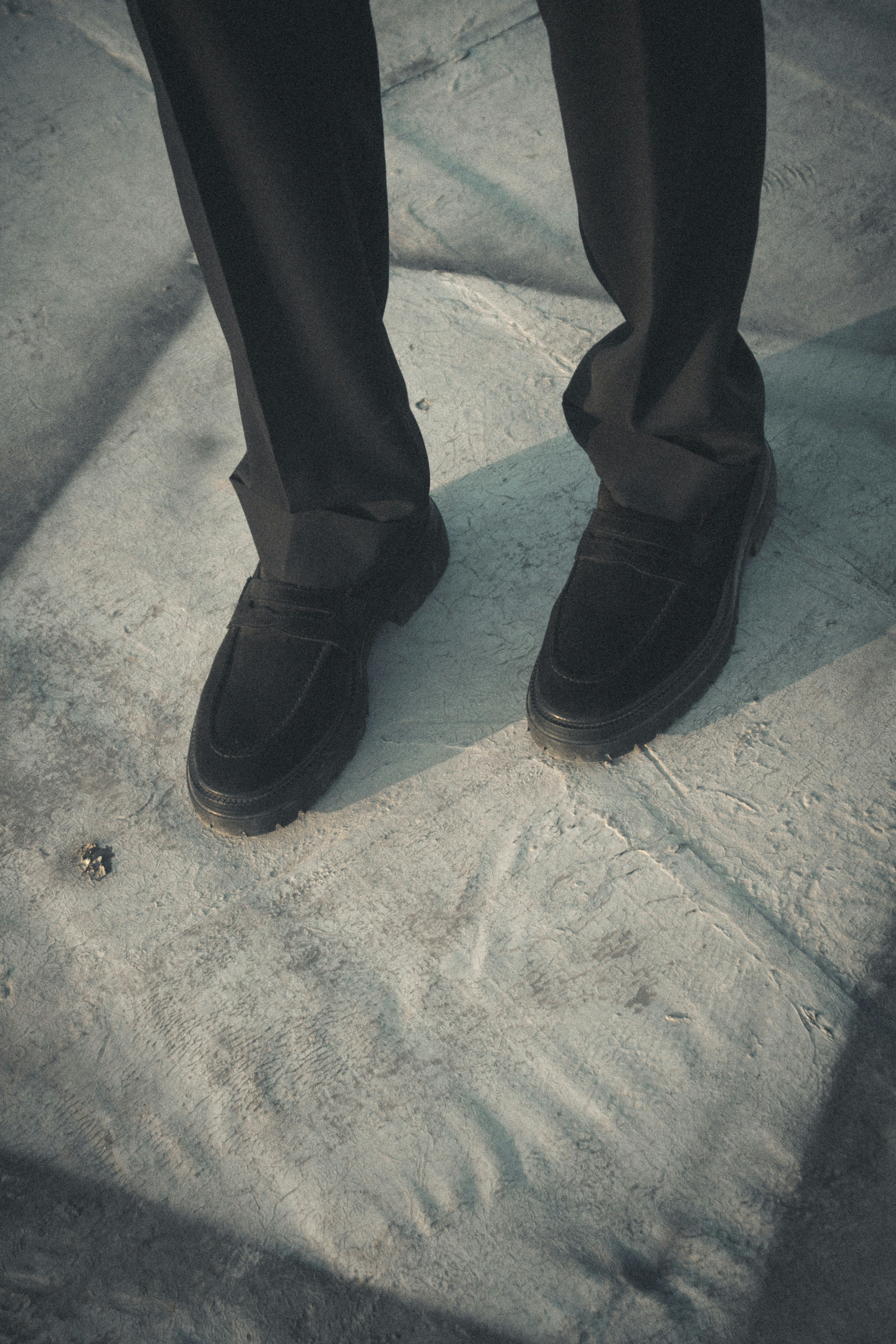 Mocassins noirs sur une personne portant un pantalon noir