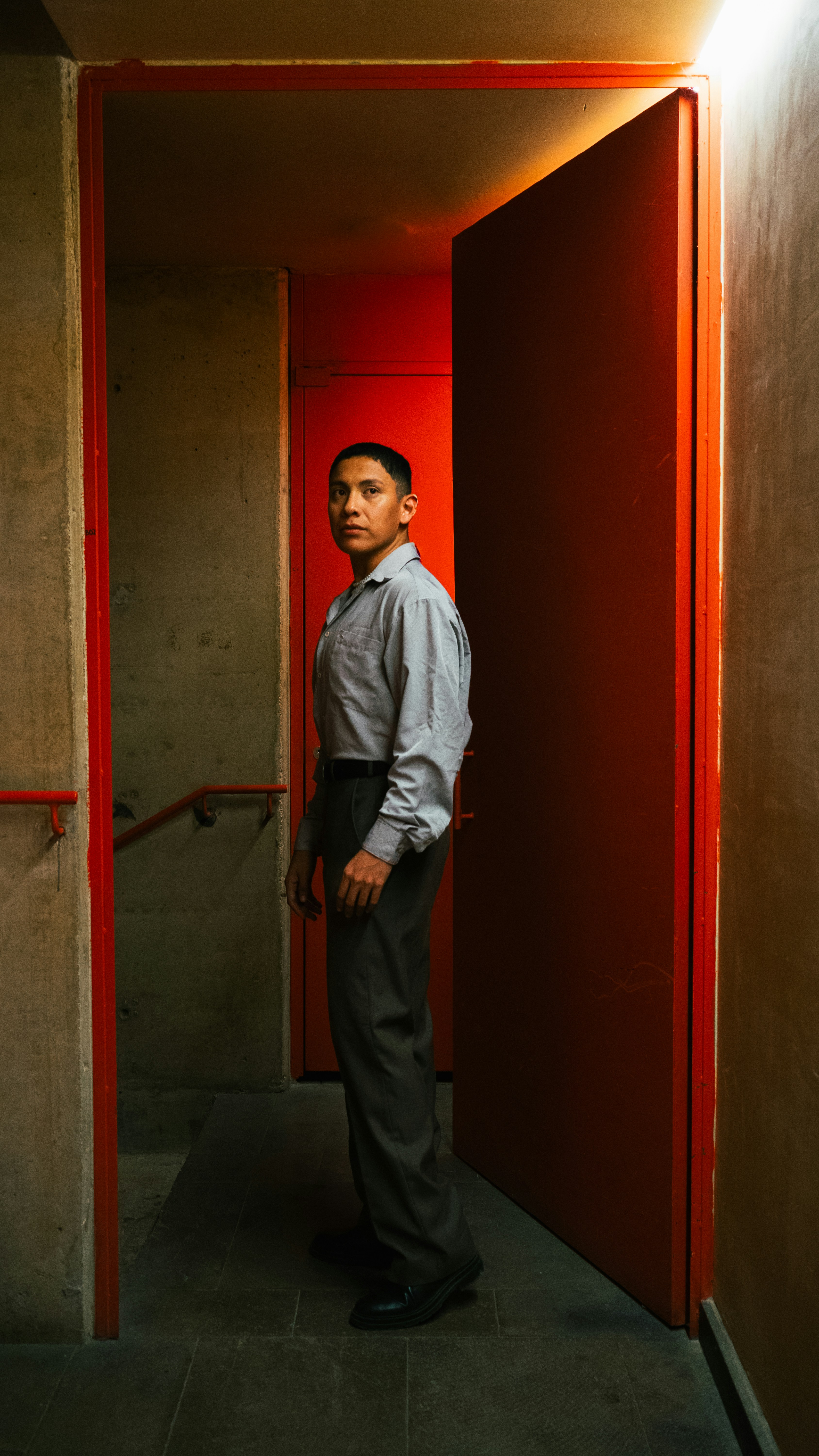 Man standing in a hallway with red doors