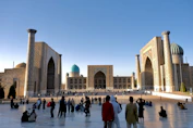 People gathered in a grand plaza with historic buildings.