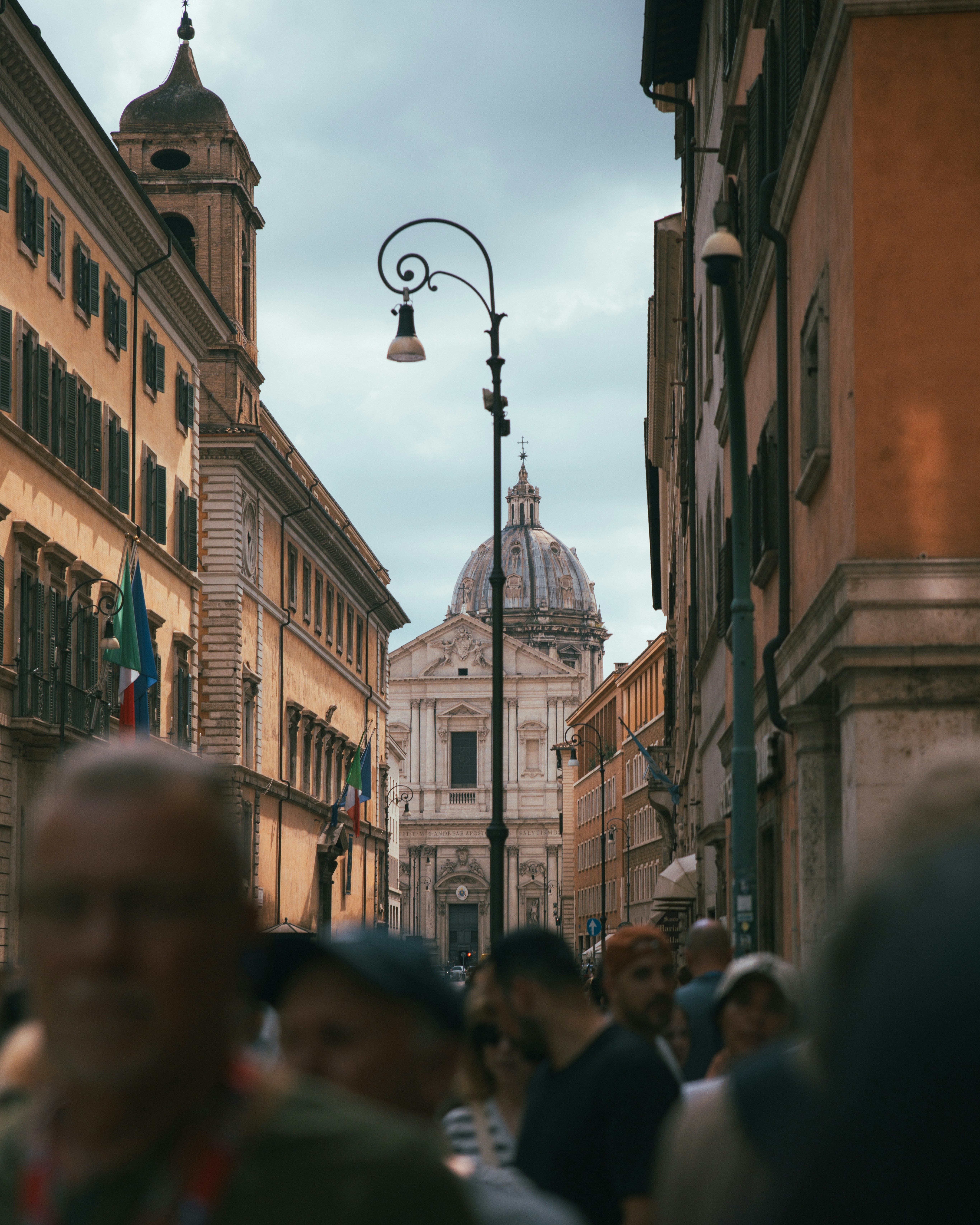 People walking on a street towards a domed building.