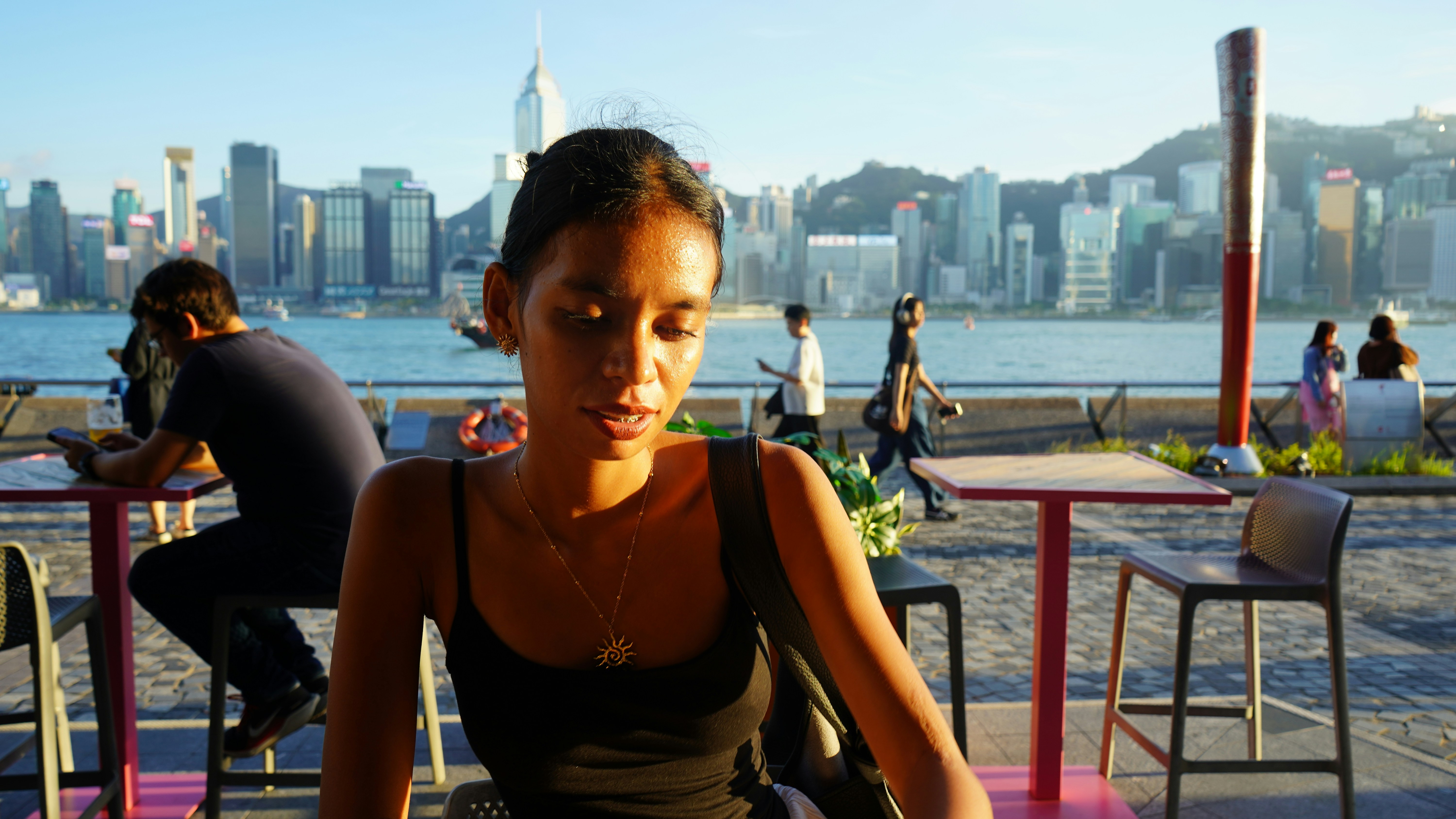 Woman sitting at outdoor cafe with city skyline background
