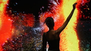 Woman silhouetted against vibrant, abstract art display