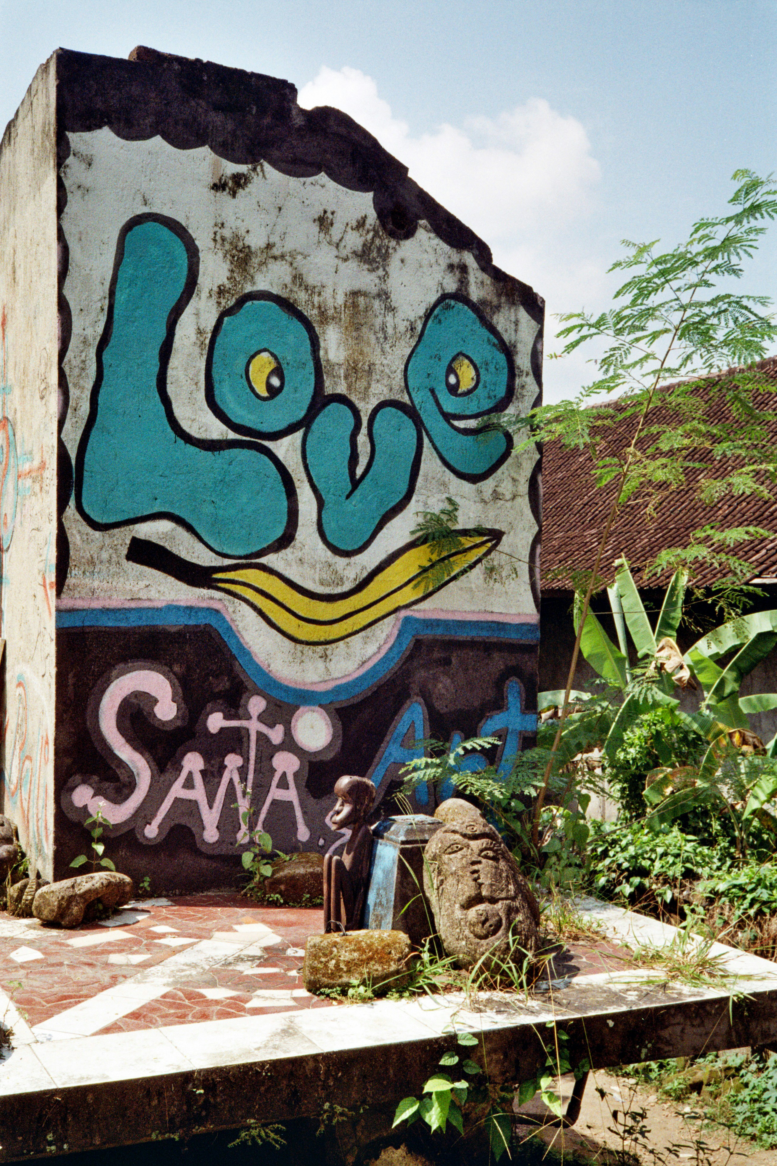 Graffiti art on a weathered wall with statues.