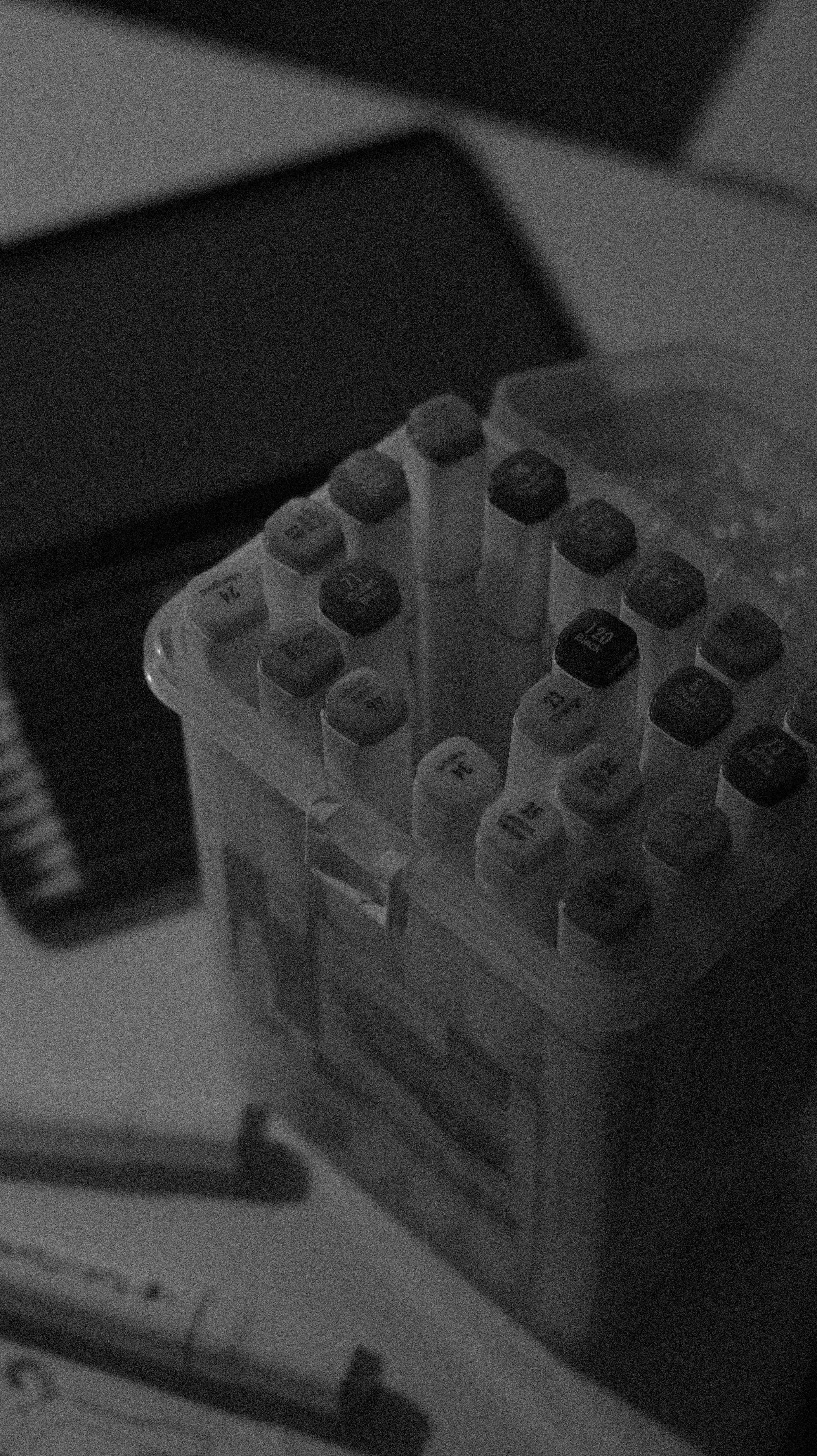 Marker pens in a clear plastic container on a table.