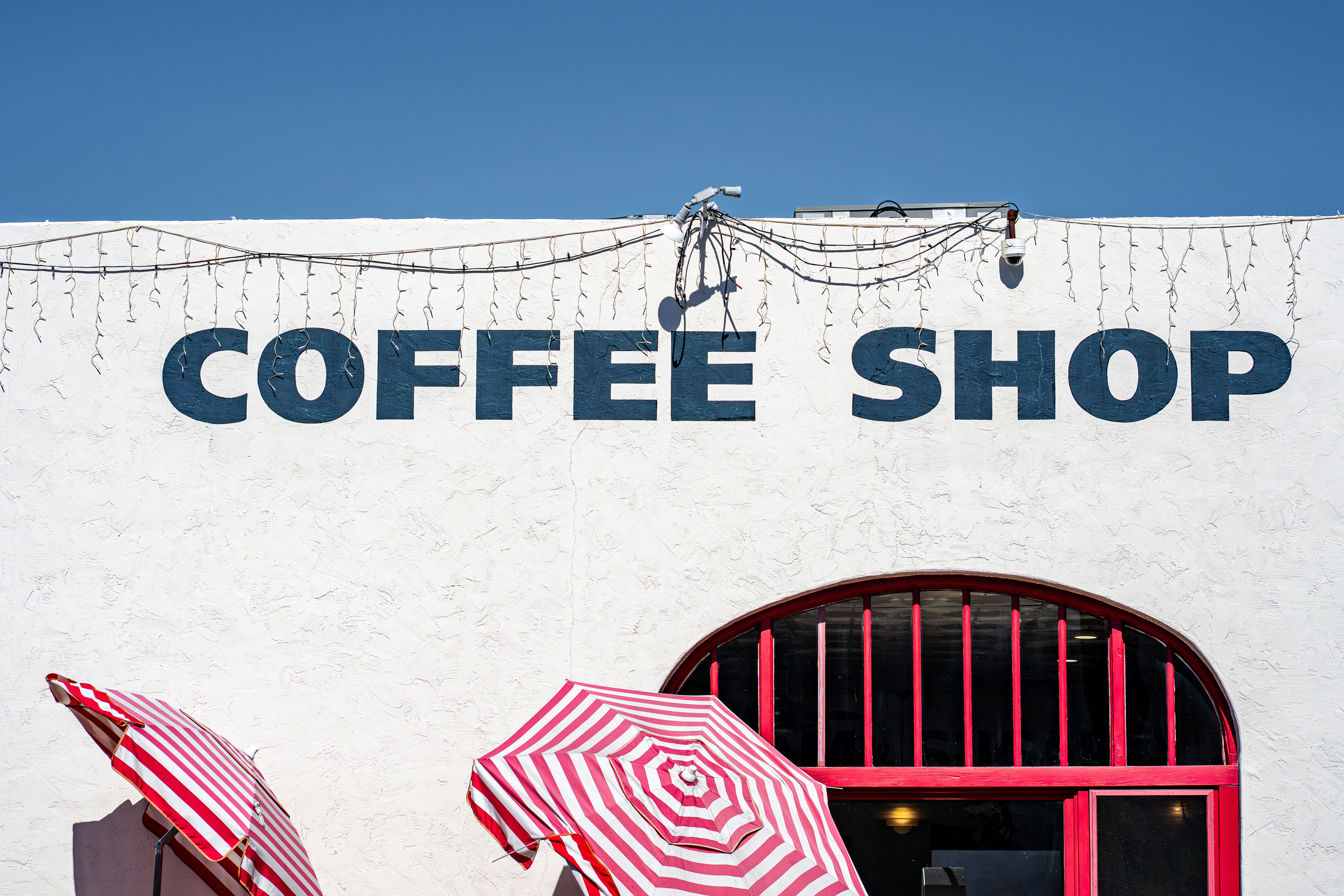 White building with "coffee shop" sign and umbrellas