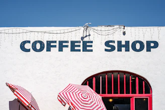 White building with "coffee shop" sign and umbrellas while walking with Jesus