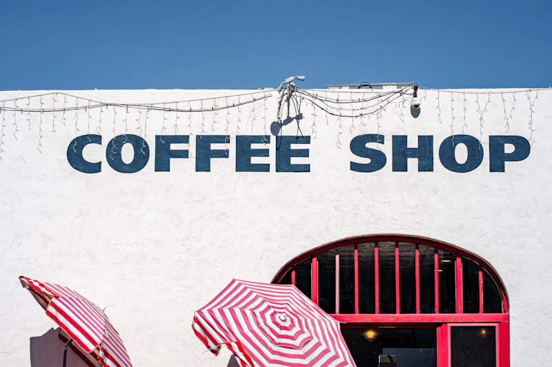 White storefront building with a clear coffee shop sign and outdoor seating