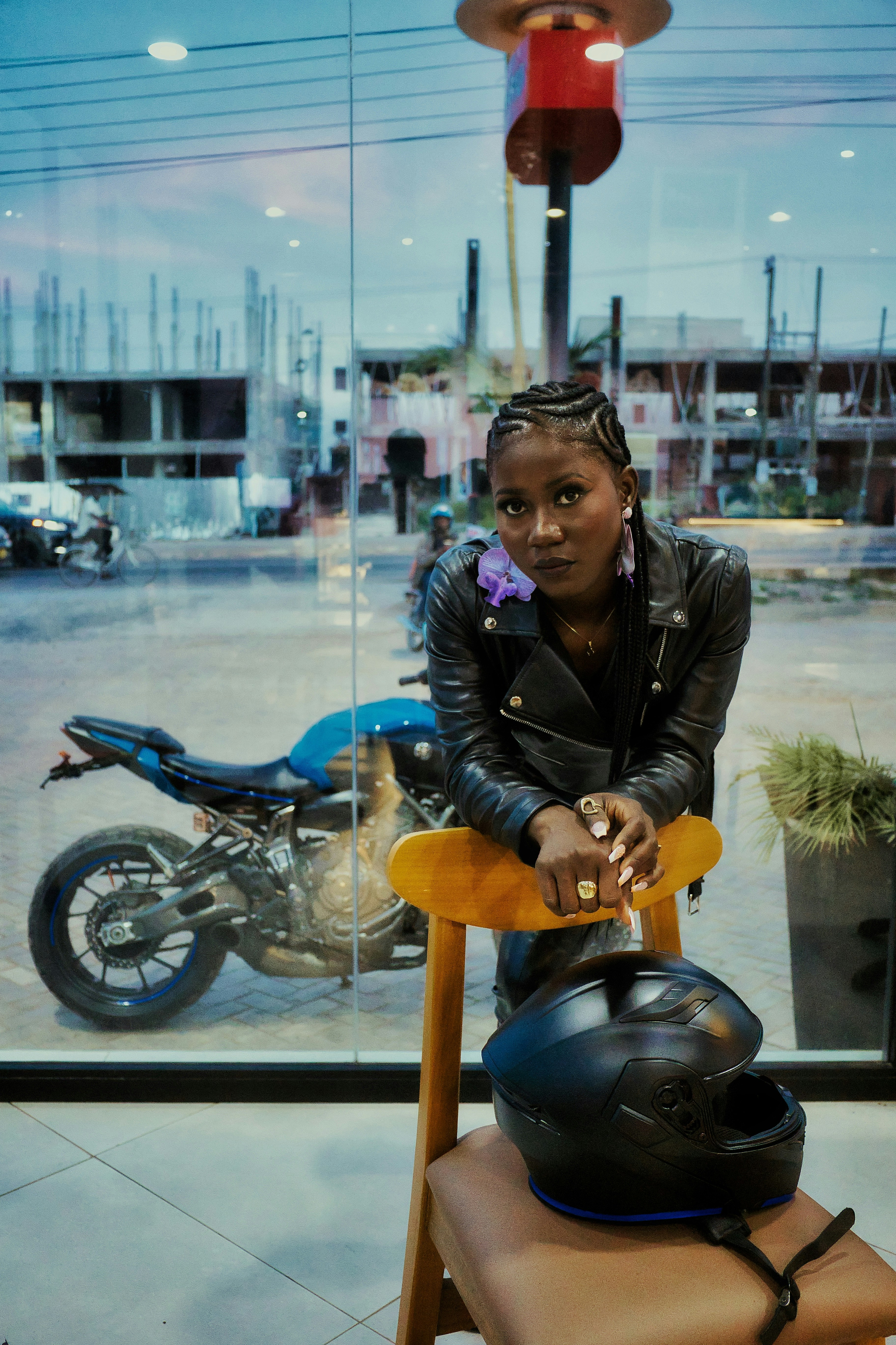Woman in leather jacket with motorcycle and helmet.