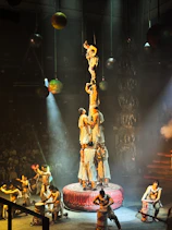 Acrobats form a human pyramid on a stage.