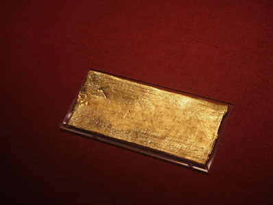 A gold bar rests on a red surface
