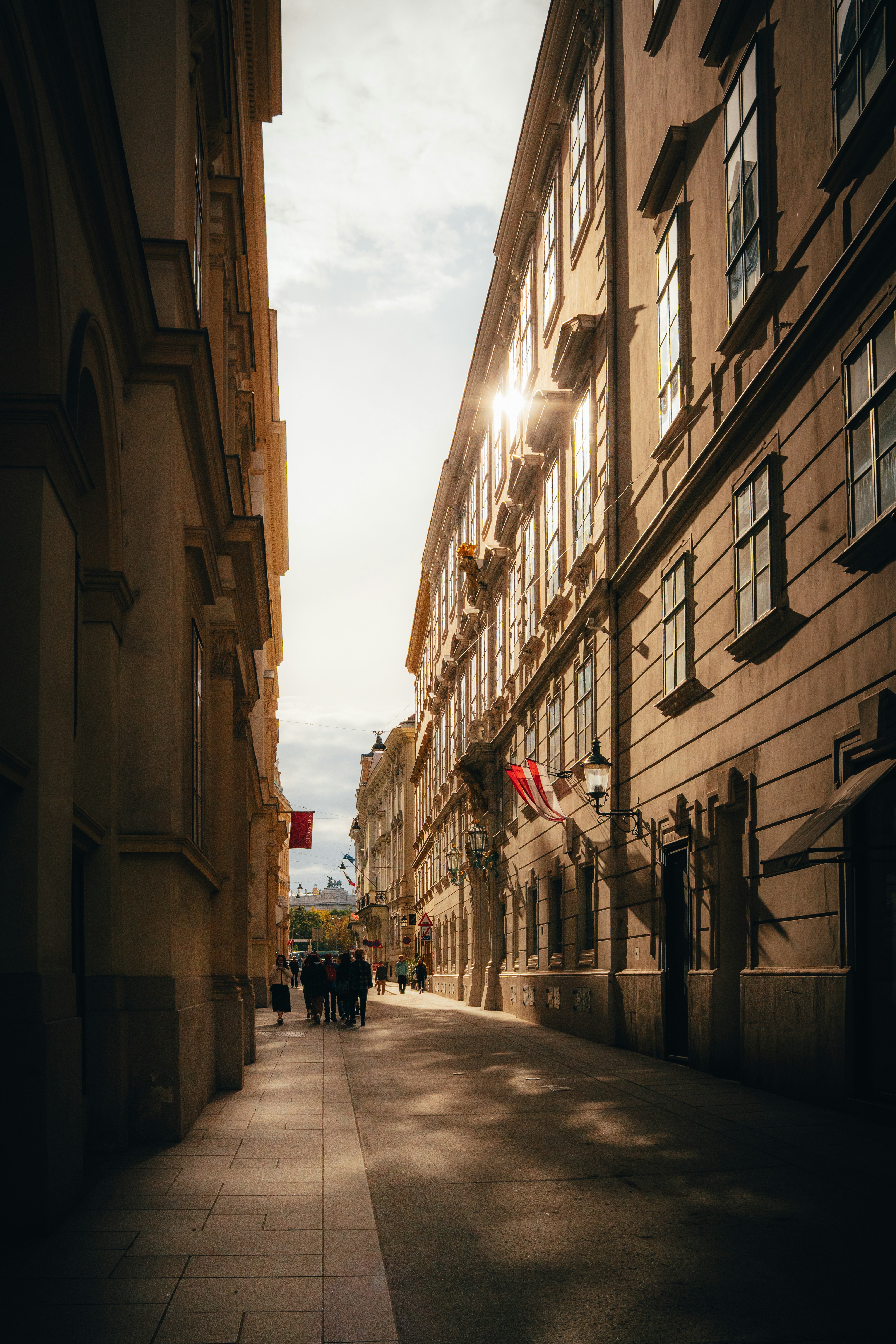 Sunlight streams down a narrow european street.