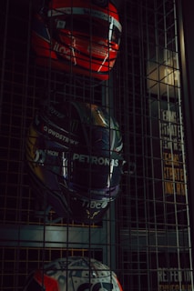 Three racing helmets displayed on a metal grate.