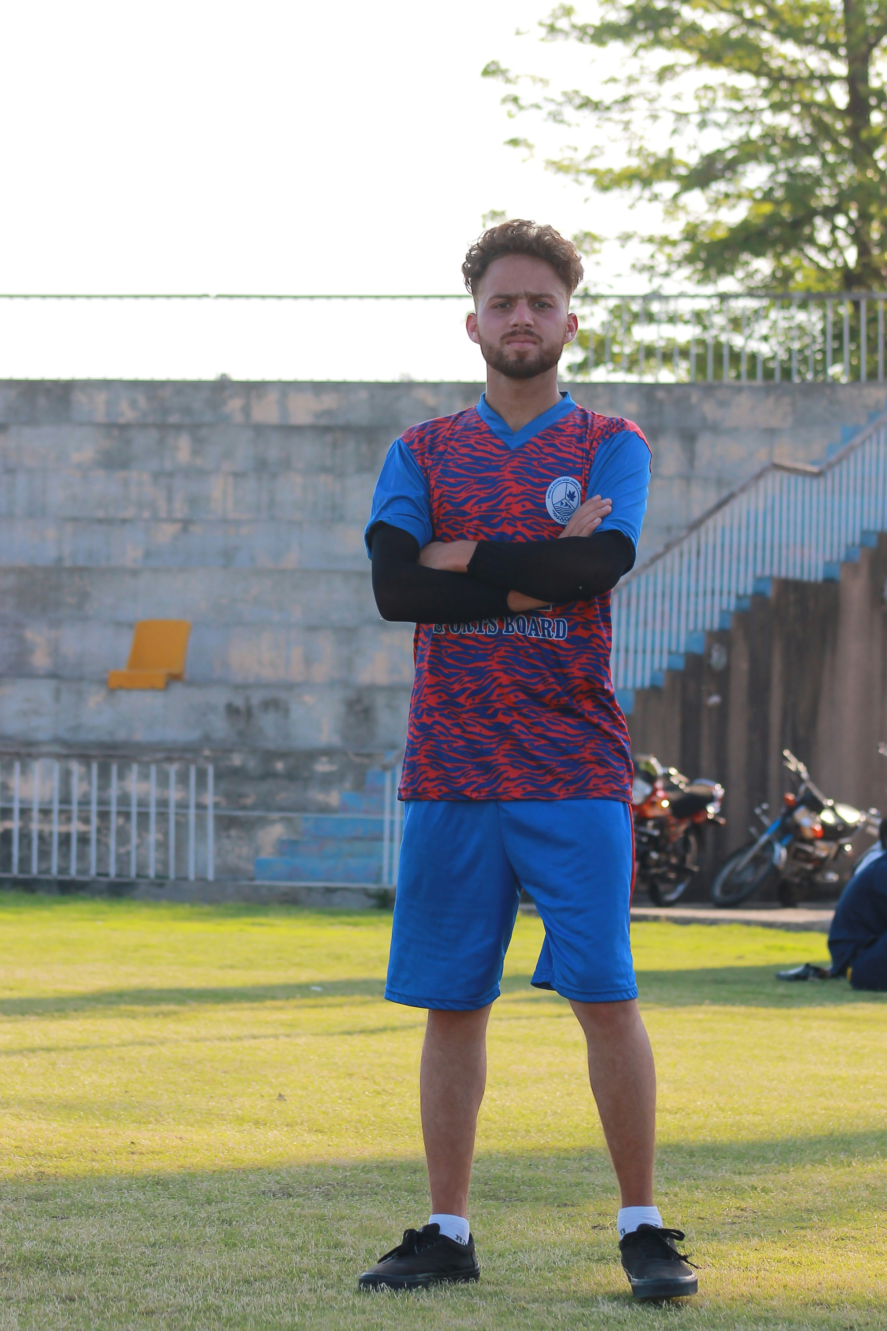 Seorang pemuda berseragam sepak bola berdiri di lapangan