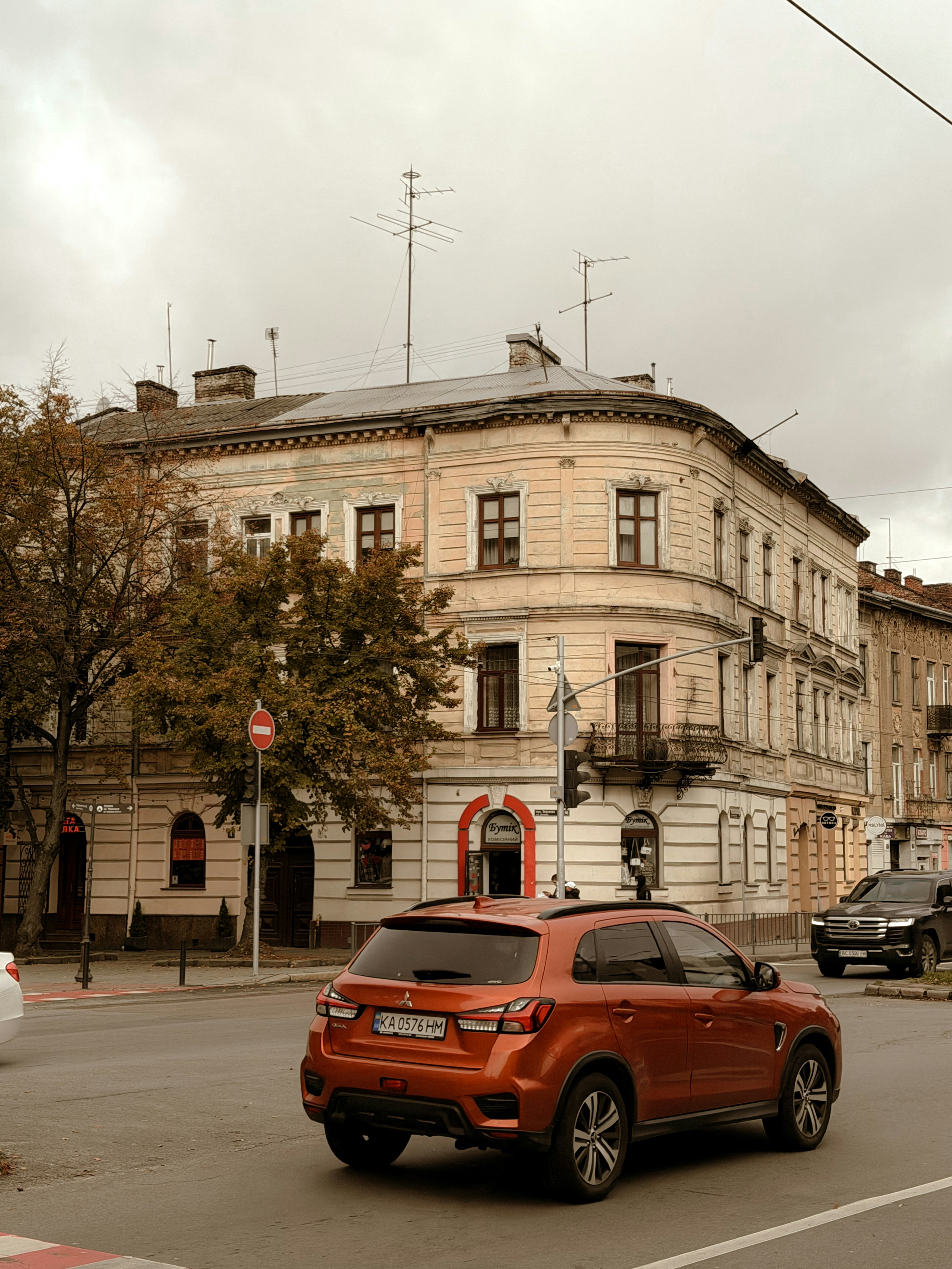 Orange car drives past old building on street