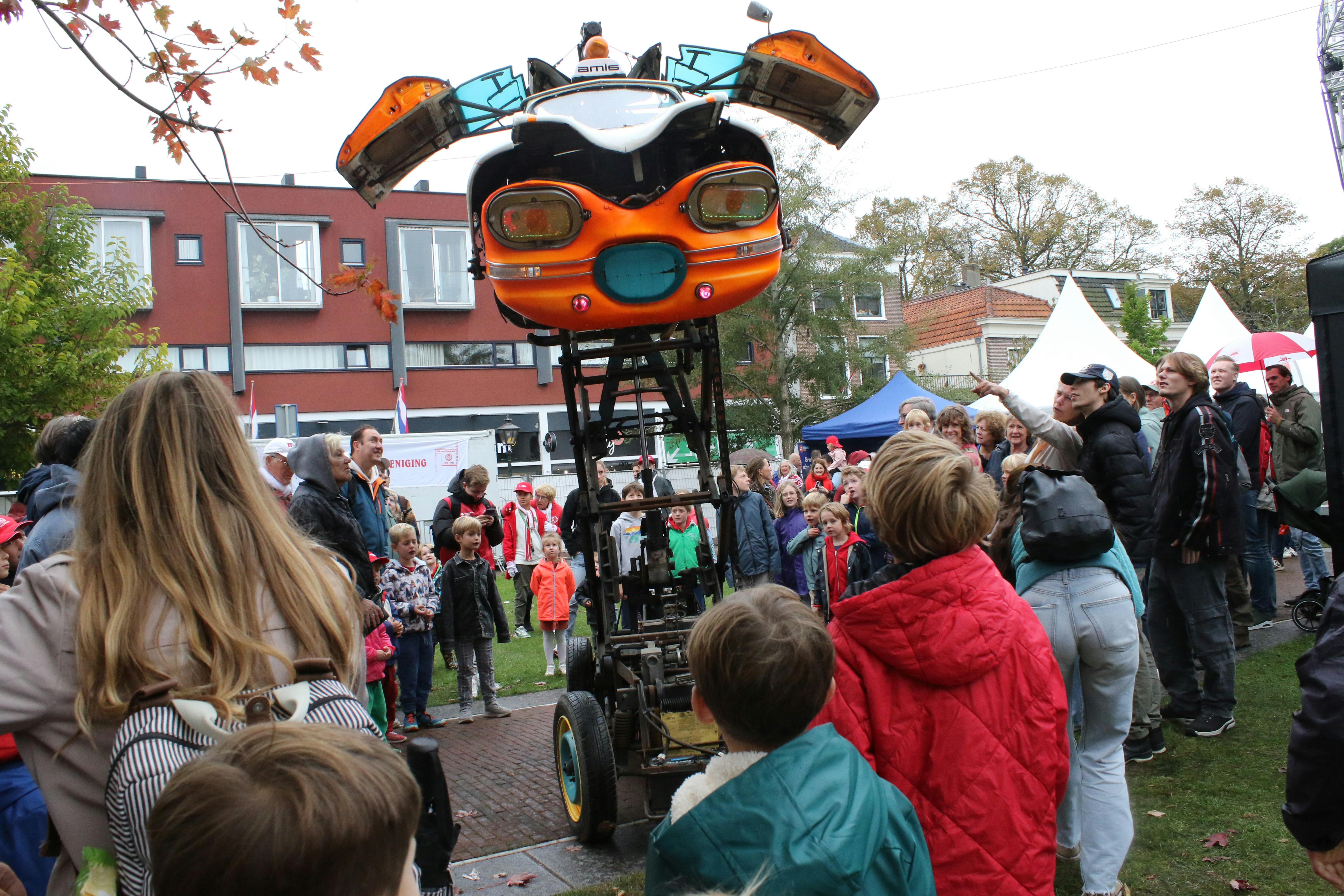 Large orange robot with people watching it