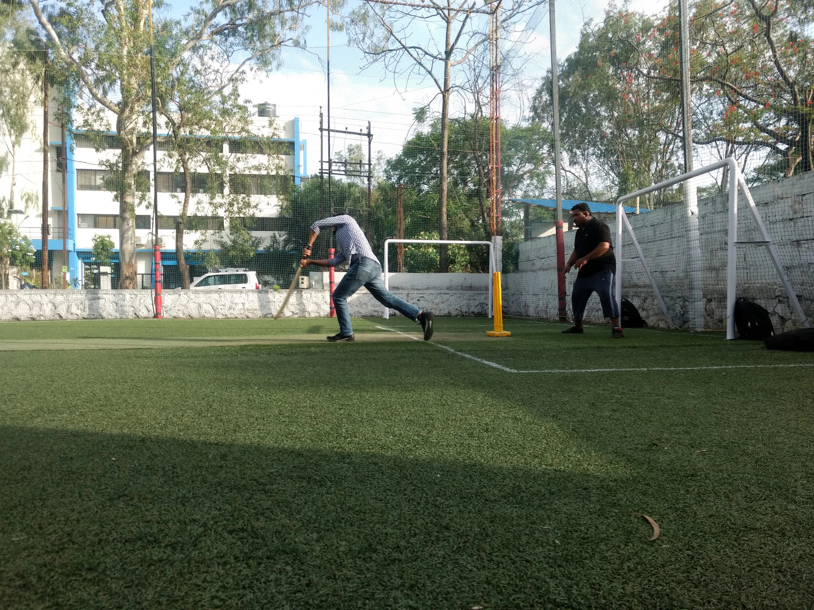 Friends playing box cricket on an enclosed turf in Gandhinagar