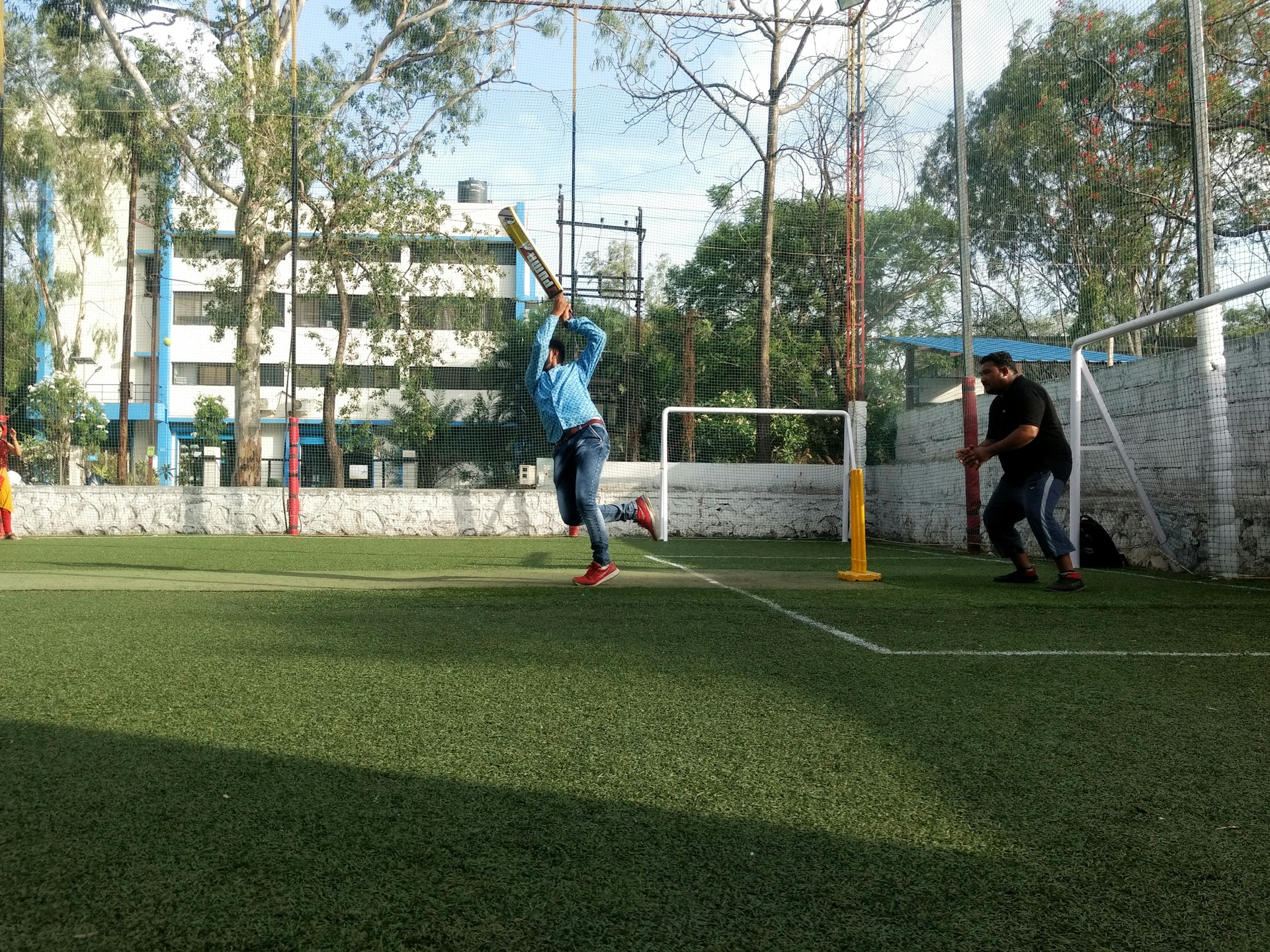A person batting during a cricket game on artificial turf.